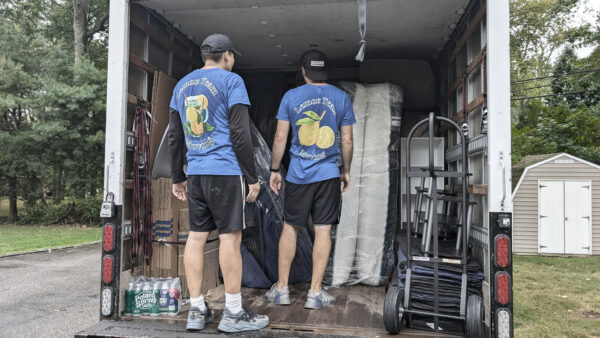 Two Lemon Team Moving crew members loading a truck with furniture, boxes, and dollies